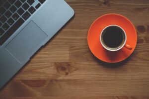 cup of coffee on table next to laptop